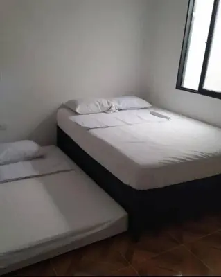 two twin beds in a room with a window at Cabaña 41, aldea Doradal Santorini Colombiano in Puerto Triunfo