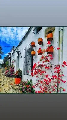 a white building with flowers on the side of it at Cabaña 41, aldea Doradal Santorini Colombiano in Puerto Triunfo