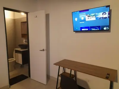 a room with a table and a television on a wall at Tribu Medellin House in Medellín