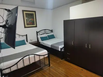 a bedroom with two beds and a dresser at HOTEL GIRASOLES in Manizales