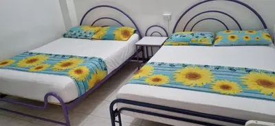 two beds in a room with sunflowers on them at HOTEL GIRASOLES in Manizales