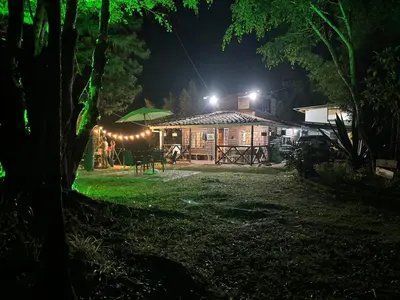 a house with a green umbrella in the yard at night at Cabaña rústica la Pradera in Guatapé