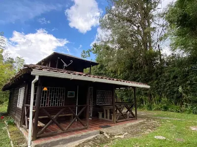 a small house with a roof on a field at Cabaña rústica la Pradera in Guatapé
