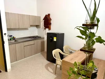 a kitchen with a black refrigerator and a table with chairs at Sol Apartamentos Doradal in Doradal
