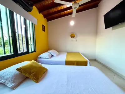 a bedroom with two beds and a flat screen tv at Sol Apartamentos Doradal in Doradal