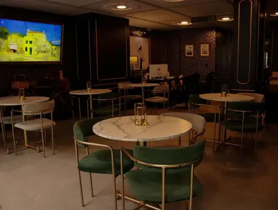 a dining room with tables and green chairs and a tv at Hotel Helene in Medellín
