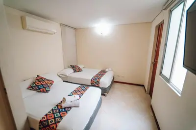 a small room with two beds and a couch at Hotel Santa Fe del Parque in Santa Fe de Antioquia