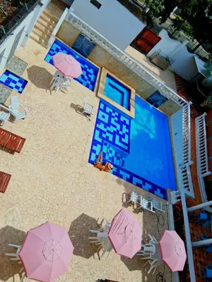 an overhead view of a beach with pink umbrellas and a pool at Hotel Santa Fe del Parque in Santa Fe de Antioquia