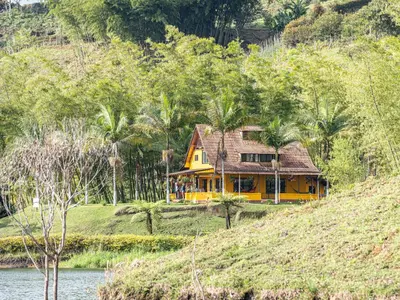 a yellow house on the side of a hill at Volare Guatapé isla de descanso y retiro in Guatapé