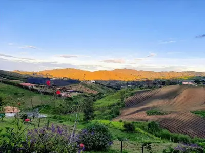 a view of a field with mountains in the background at Casa de Campo vía El Peñol Guatapé in Marinilla