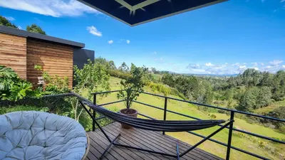 a hammock on the deck of a house with a view at Cumbres Luxury Glamping in Guarne