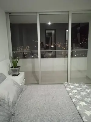 a bedroom with a view of a city at night at Penthouse Lujo Itagui 40 Piso Vista Panoramica Jacuzzi Sauna Largo Plazo in Itagüí