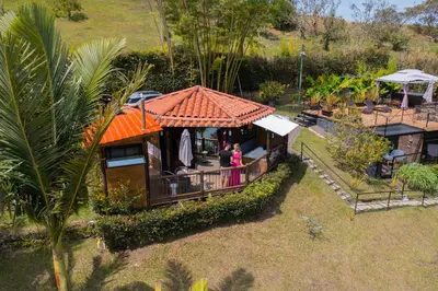 a house with an orange roof with two people standing on a porch at Cottage Master Room en Guatapé-Desayuno- Sauna Finlandes in Chiquinquirá
