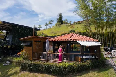 a woman standing on a porch of a house at Cottage Master Room en Guatapé-Desayuno- Sauna Finlandes in Chiquinquirá