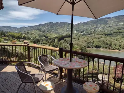 a table with chairs and an umbrella on a balcony at Cottage Master Room en Guatapé-Desayuno- Sauna Finlandes in Chiquinquirá
