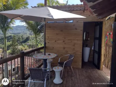 a table and chairs on a balcony with an umbrella at Cottage Master Room en Guatapé-Desayuno- Sauna Finlandes in Chiquinquirá