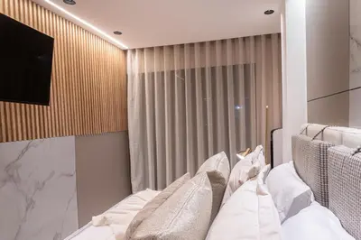 a bedroom with a bed with white pillows and a television at Jacuzzi Privado, Casa de Lujo Norte Medellin in Medellín