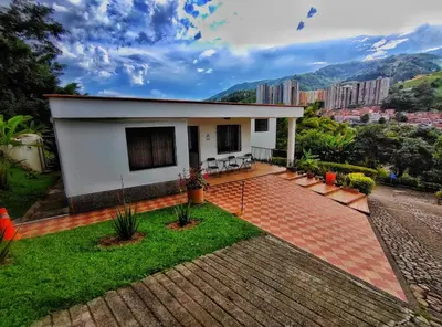 a small white house with a patio and grass at Gran Tierra - Sabaneta in Medellín