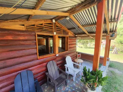 a wooden cabin with two chairs and a table at Cabañas la tierra prometida in Cisneros