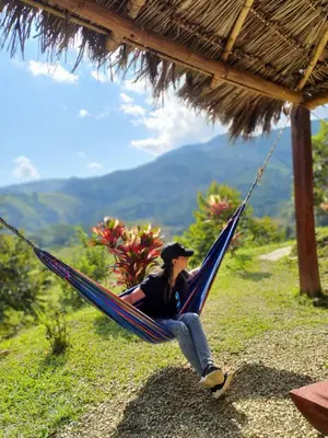 a woman sitting in a hammock on a hill at Cabañas la tierra prometida in Cisneros