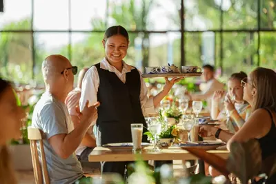 a waitress holding a tray of food in a restaurant at Alfahar Hotel in Carmen de Viboral