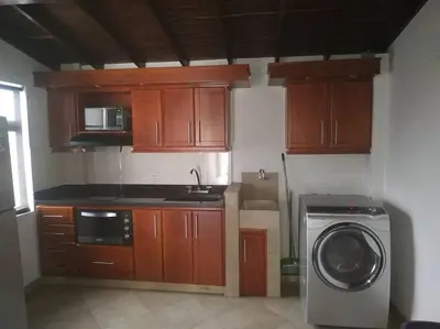 a kitchen with a washing machine and wooden cabinets at Hermoso apartamento totalmente amoblado in Medellín
