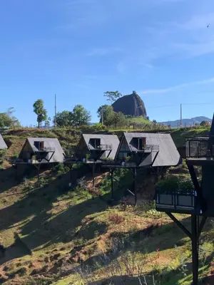 a row of houses in a field with a rock in the background at GRETEL CHALETS SUIZO in Guatapé
