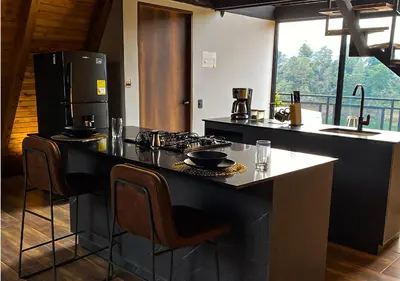 a kitchen with a counter with a stove and a refrigerator at GRETEL CHALETS SUIZO in Guatapé