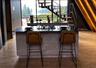 a kitchen with a counter with two bar stools at GRETEL CHALETS SUIZO in Guatapé
