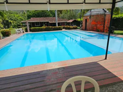 a large blue swimming pool with a chair and an umbrella at Finca la Querendona in Santa Fe de Antioquia