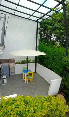 a patio with a table and a white umbrella at Bird House - Apartament in Jardin