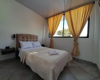 a bedroom with a large bed and two windows at Katara Boutique Hotel in Mariquita