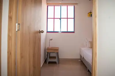 a bedroom with a bed and a table and a window at Apartamento amplio cerca al parque Guatape - Pajaros in Guatapé