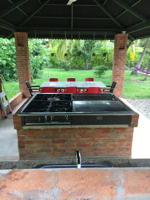 a grill on a brick island in a patio at Casa Guali in Honda