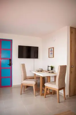 a dining room with a table and chairs and a tv at Cozy Apartment Rocks Guatape in Guatapé