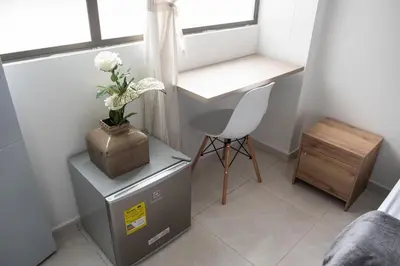 a small room with a desk and a table with a flower on it at Descansa en Habitación Privada en Medellín C in Medellín