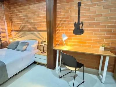 a bedroom with a bed and a guitar on a brick wall at Apartamento en Laurels Medellín in Medellín