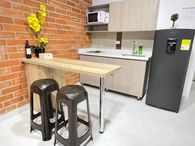 a kitchen with a table and two stools and a refrigerator at Apartamento en Laurels Medellín in Medellín
