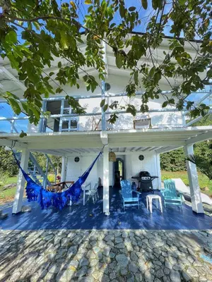 a white house with a porch with chairs and a grill at Hermosa Casa frente al Río in San Rafael