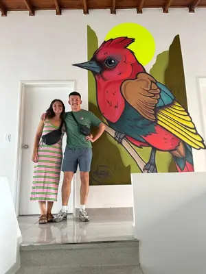 a man and woman standing in front of a painting of a bird at Gaston2 in Medellín