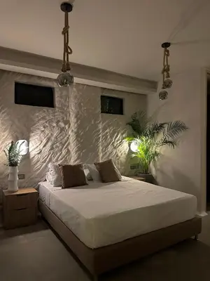 a bedroom with a white bed with a stone wall at HOTEL BALI AT POBLADO in Medellín