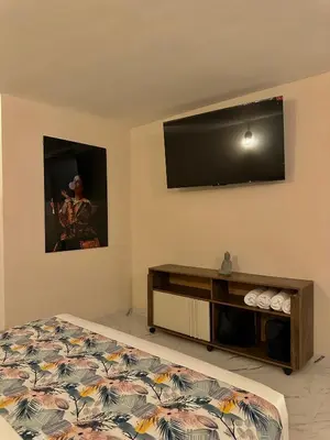 a bedroom with a bed and a flat screen tv at HOTEL BALI AT POBLADO in Medellín