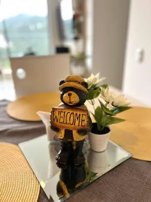 a teddy bear holding a welcome sign on a plate with flowers at Espectacular vista cerca a cable plaza con Piscina in Manizales