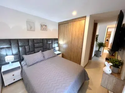 a bedroom with a large bed and a television at Espectacular vista cerca a cable plaza con Piscina in Manizales