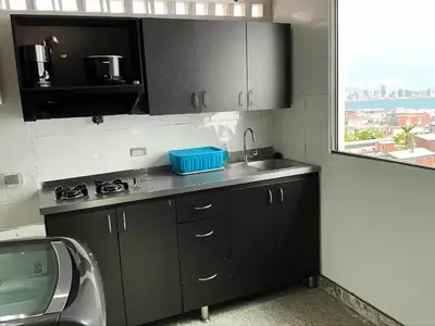a kitchen with black cabinets and a sink and a window at Aparta Suite Torre De Prado Penthouse in Medellín