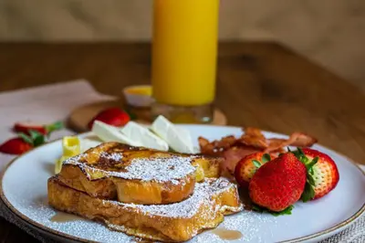 a white plate with french toast and fruit on a table at Valerio Hotel Boutique in Marinilla