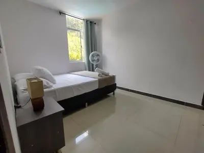 a bedroom with a bed and a window with a fan at RentalsOP AN01 Apto cerca al lleras con balcon y piscina climatizada, cerca a provenza, ubicado min del aeropuerto in Medellín
