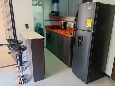 a kitchen with a stainless steel refrigerator and a bar stool at RentalsOP AN01 Apto cerca al lleras con balcon y piscina climatizada, cerca a provenza, ubicado min del aeropuerto in Medellín
