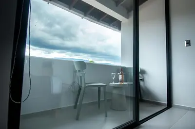 a glass balcony with a chair and a table at Barcelo Coliving in Medellín