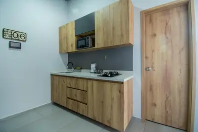 a small kitchen with wooden cabinets and a door at Barcelo Coliving in Medellín